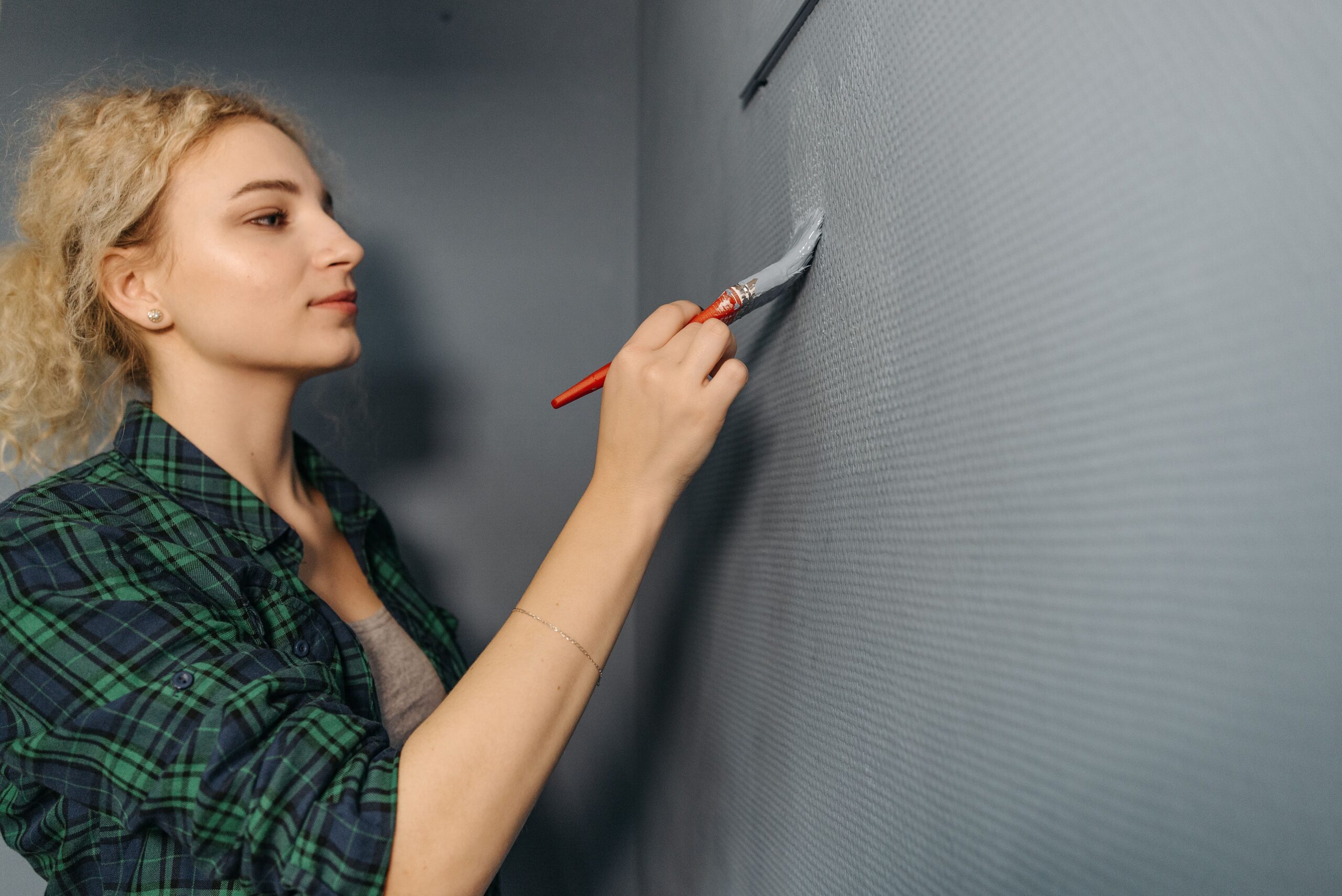 Femme en train de peindre un mur intérieur en gris lors d'une rénovation